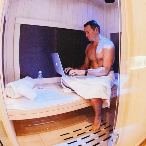 Man typing on lapton in Infrared Sauna.