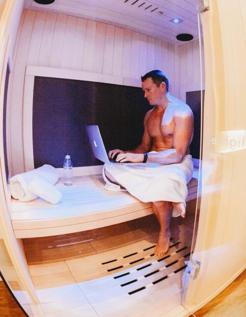 Man typing on lapton in Infrared Sauna.
