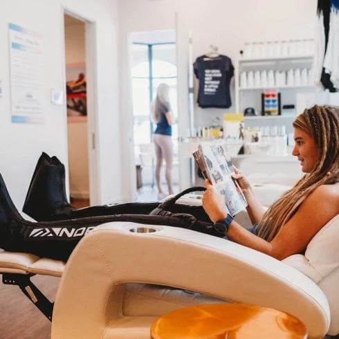 Woman in chair receiving NormaTec Compression treatment.