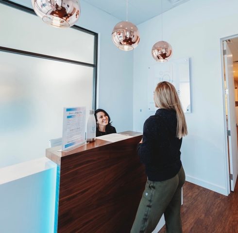 A woman standing at the receptionist desk at Degree Wellness.