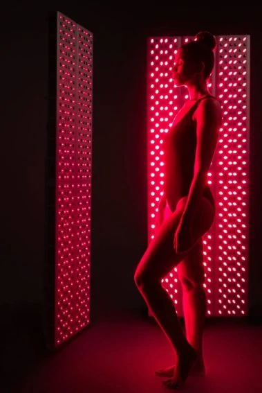 Woman standing with eyes closed receiving Joovv Red Light Therapy.