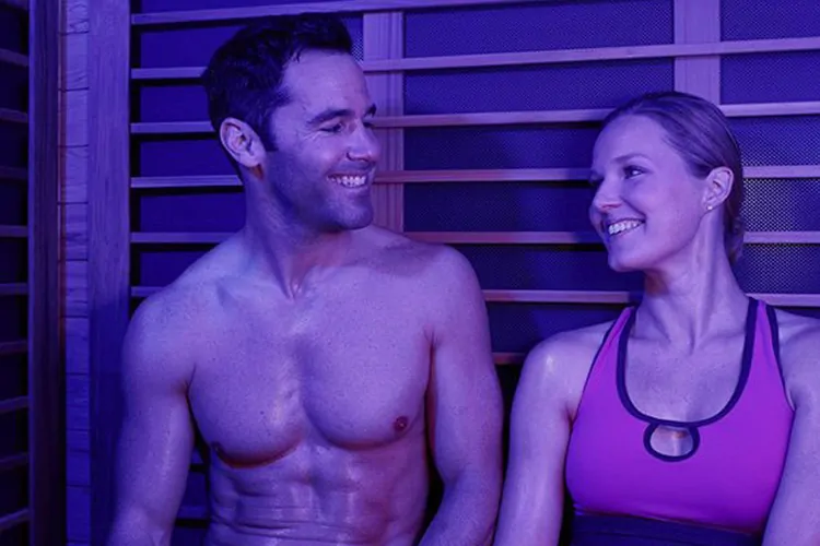 Smiling man and woman sitting in infrared sauna.
